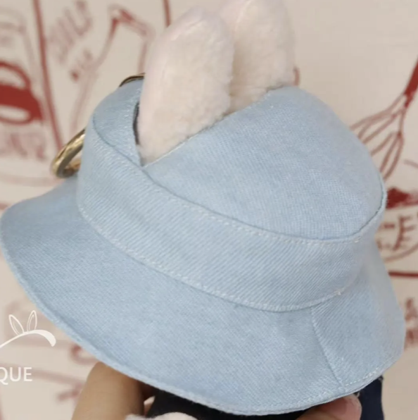 Light blue visor hat held by a hand against a patterned background